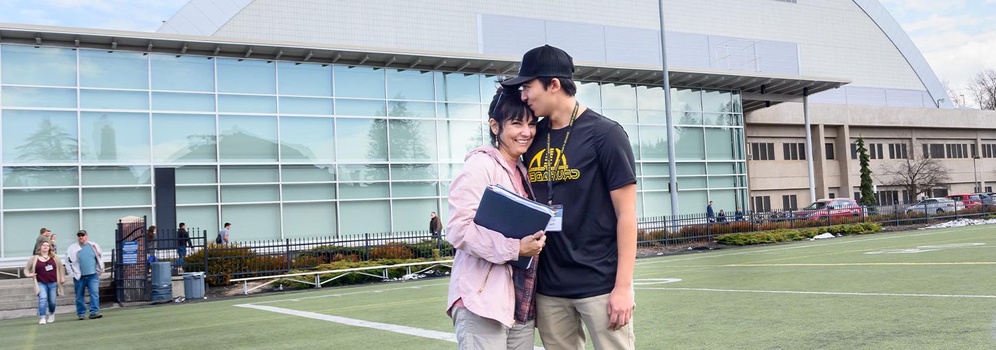 A student hugs his mother outside of the Kibbie Dome