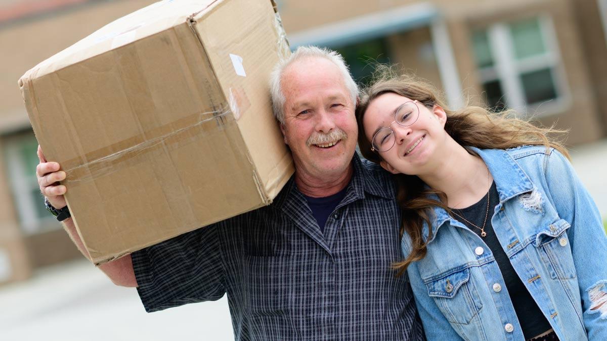 A student with their father holding a box
