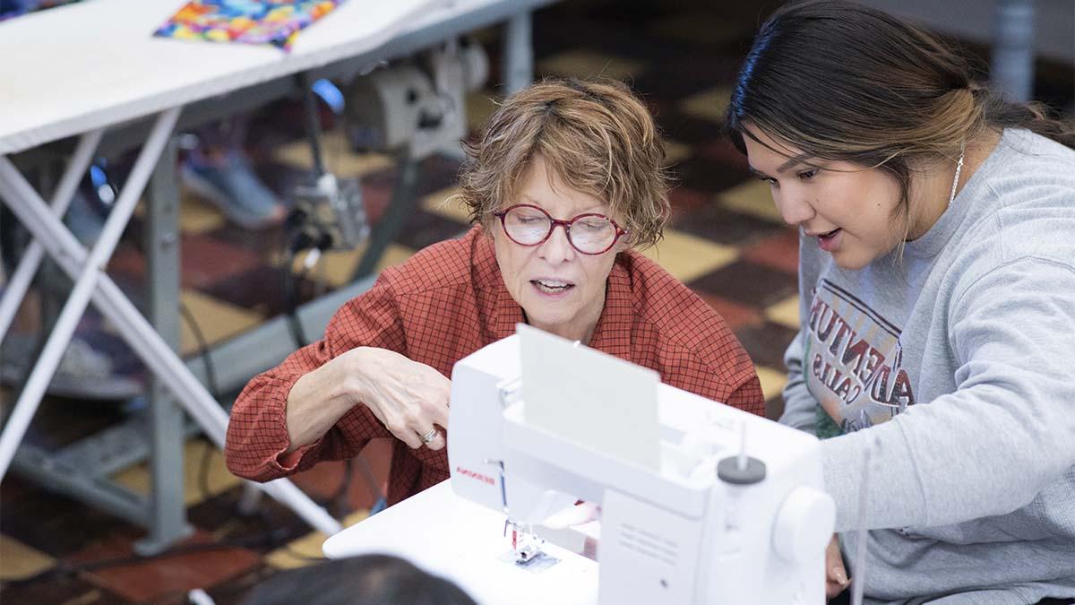 一位妇女教学生如何使用缝纫机.