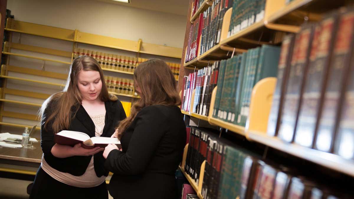 两个法律系学生在图书馆的书架旁看书