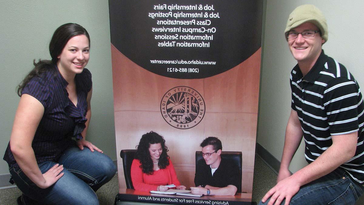 Interns kneel next to a retractable banner they made for the office