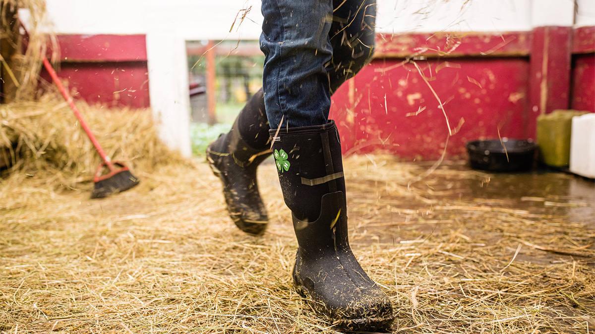 A person wearing boots walking on hay.