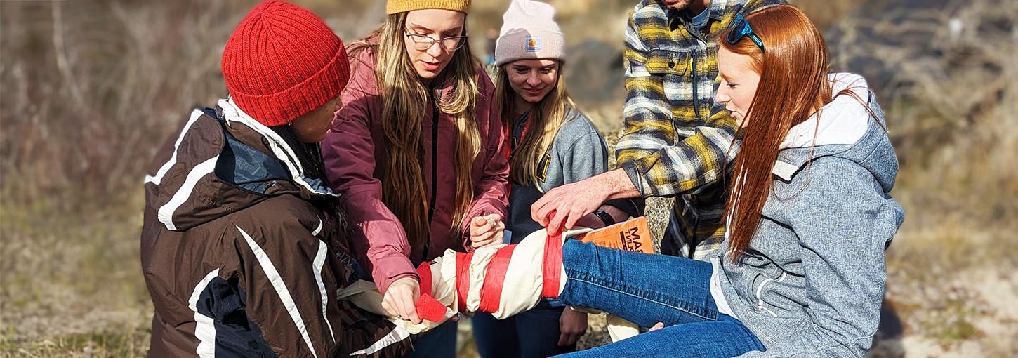 Idaho WWAMI students tie a leg brace around a volunteer victim during a medical simulation.